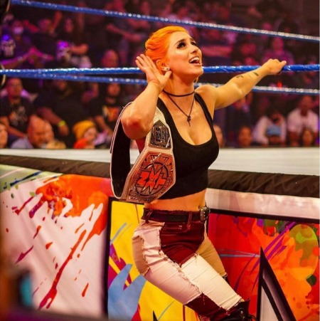 The American wrestler Gigi Dolin holding the NXT Women's Tag Team Champion Belt.